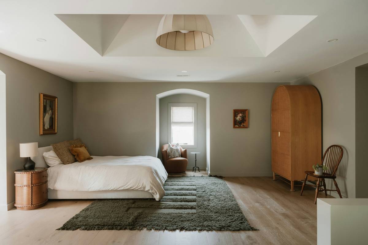 minimalist interior design bedroom featuring a low platform bed, linen bedding, and a single wooden nightstand with soft ambient lighting